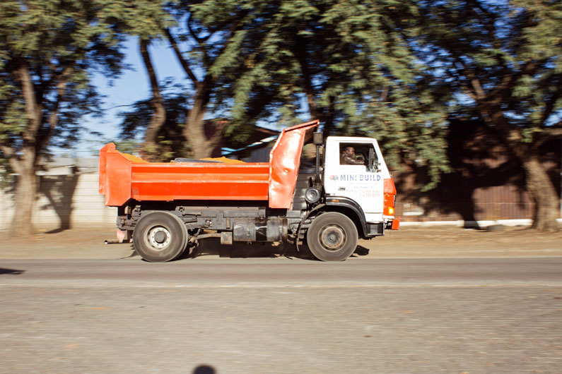 Mini Build truck loaded with building material driving down the road