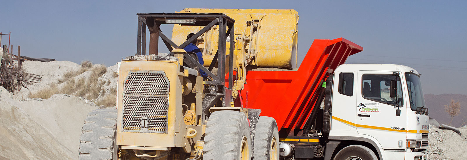 TLB machine loading building sand on a Mini Build Truck